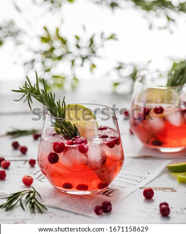 lemonade with cranberries, lime and rosemary in a transparent glass