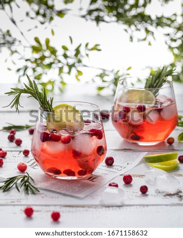 lemonade with cranberries, lime and rosemary in a transparent glass