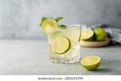 Lemonade drink with fresh lime on a texture  background. Refreshing cocktail mojito with citrus fruits, mint and ice. Summer cold drink concept. Front view and copy space.. - Powered by Shutterstock