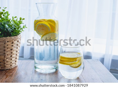 lemonade in a glass bottle on a wooden table. Summer refreshing drink. Cold detox water with lemon. 