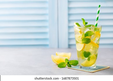 Lemonade, Lemon Ice Tea, Mint Cocktail In Glass. Blue Background. Close Up. Copy Space.