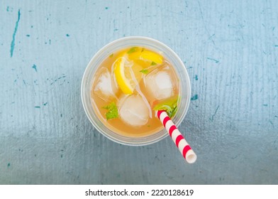 Lemonade With Lemon Slices, Ice Cubes And A Colorfully Striped Straw On A Blue Table, Top Down View