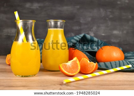 Lemonade made from citrus fruits in small bottle jars with drinking straws and fruit slices on wooden table