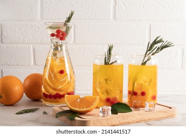 lemonade from orange and berries in two modern glasses in the form of a can and a carafe on a table against a brick wall - Powered by Shutterstock