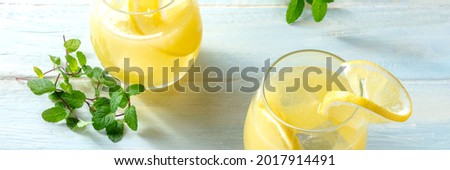 Lemonade panorama on a wooden background. Homemade fresh drink with lemon and mint. Healthy organic detox beverage