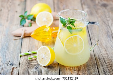 Lemonade pitcher with lemon, mint and ice on table. - Powered by Shutterstock