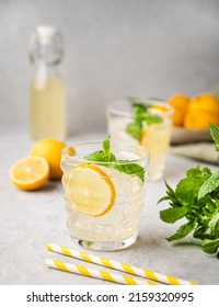 Lemonade soda drink with fresh lemons. Refreshing cocktail with lemon, mint and ice on textured light background. Summer cold drinks concept. - Shutterstock ID 2159320995