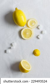 Lemons And Sugar Cubes Over White Cloth. Overhead View