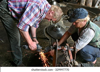 Lemozero, Olonets, Karelia, Russia - July 26, 2006: Two Farmers Farm Tractor Mowing-machine Repaired In A Repair Shop, Sharpening Knives Using A Grinding Machine.