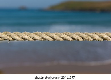 Length Of Rope Pulled Tight Against A Blurred Background Of Sea And Coast