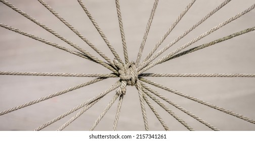 Lengths Of Nautical Rope Tied Together, Creating A Radial Pattern, As A Decorative Barrier Along A Town Waterfront On A Sunny Afternoon, For Concepts Of Unity, Teamwork, Commonality