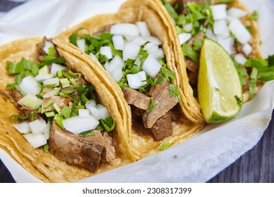 Lengua de carne de vaca tres tacos callejeros mexicanos con cilantro, tima cuña y cebolla