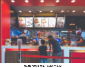 Lens blurry and vintage images of Front view of fried chicken counter, Female customers with children are standing, choosing the fried chicken menu. and the salesperson is standing to receive orders.