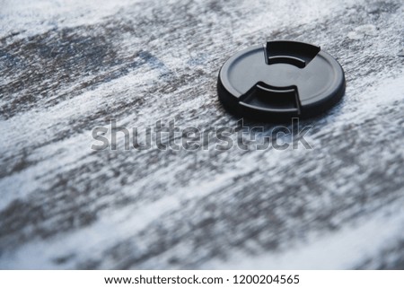 lens cap selective focus or Black unbranded DSLR lens cap, isolated on wooden background