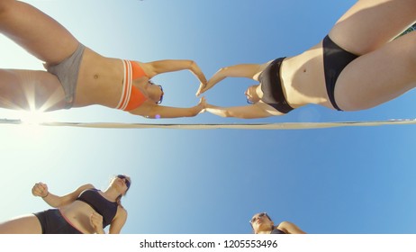 LENS FLARE, BOTTOM UP: Cheerful female beach volleyball players jump and high five after scoring a point in a summer tournament. Athletic young Caucasian women celebrating their win in volleyball game - Powered by Shutterstock