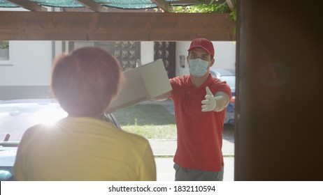 LENS FLARE, CLOSE UP: Young Caucasian Courier Throws A Package To Elderly Woman Answering The Doorbell, Delivery Guy Wearing A Facemask Tosses A Box To Senior Lady During Covid 19 Social Distancing.