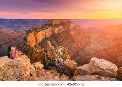 (Lens flare effect) A group of people was sitting near the edge watching sunset at Grand Canyon National Park North Rim, USA. Grand Canyon National Park is one of the world's natural wonders