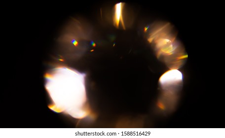 Lens Flare, Round Diamond Abstract Bokeh Golden Holiday Lights. Leaking Reflection Of A Glass, Crystal, Defocused Shining, Glowing Colorful Rainbow Christmas Light Leaks, Rays On Black Background