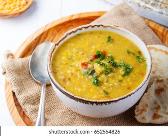 Lentil soup with pita bread in a ceramic white bowl on a wooden background. Close up.