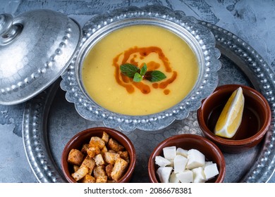 Lentil soup with spices, herbs, bread in a rustic metal bowl served with cheese,lemoon and croutons.