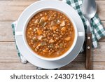 Lentil soup with vegetables in bowl on wooden table. Top view