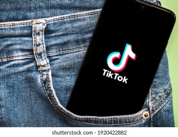 Leon-Spain-19 February 2021.Tik Tok Logo On Black Screen Of Smartphone In Jeans Pocket On A Green Background