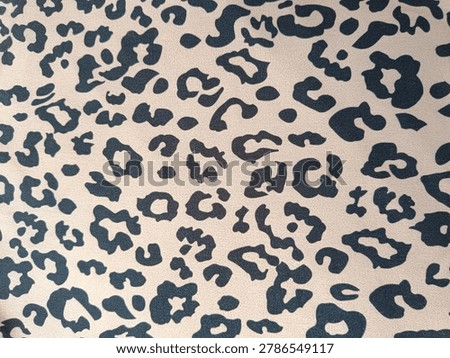 Leopard print fabric texture background. Classic animal spotted pattern on beige clothing material.