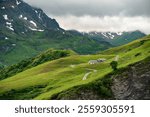 LES CHAPIEUX , Alps, France, Tour du Mont Blanc - the mountain shelter and farm near Cormet de Roselend  with high peaks in background and a winding road
