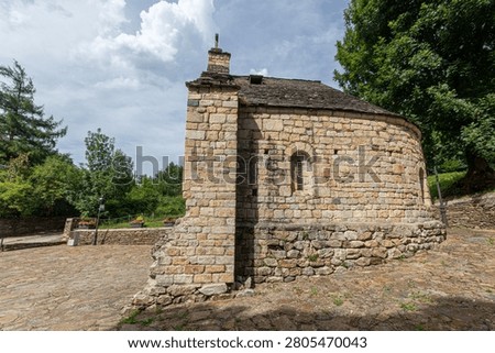 Les, Spain. Side view of the twelfth century Romanesque chapel of Sant Blasi in Aran Valley, showing its semicircular stone apse, a narrow window, and remnants of an older structure