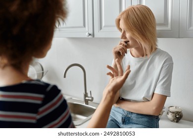 A lesbian couple argues in the kitchen, their faces showing displeasure and frustration. - Powered by Shutterstock