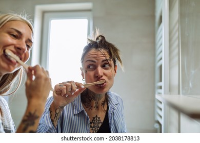 Lesbian couple brushing their teeth together in the bathroom at home - Powered by Shutterstock