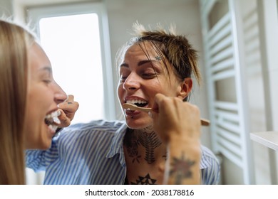 Lesbian couple brushing their teeth together in the bathroom at home - Powered by Shutterstock