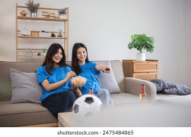 Lesbian Couple Cheering for Football Together at Home, Enjoying Snacks and Drinks, Celebrating Sports Enthusiasm, LGBTQ Representation, Happy Moments, Cozy Living Room, Modern Lifestyle - Powered by Shutterstock