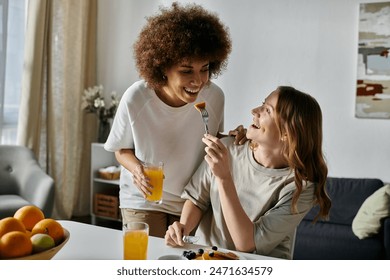 A lesbian couple enjoys a breakfast together at home, laughing and sharing a meal. - Powered by Shutterstock