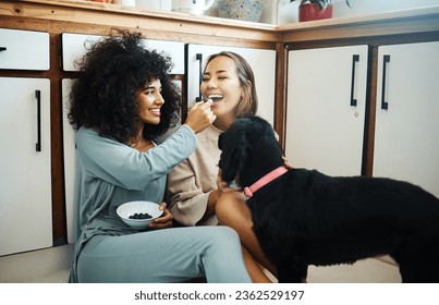 Lesbian, couple and happy with dog in kitchen, home or women eating breakfast together on the floor of apartment. Pet, animal and people with cereal or food in house with love, care and support - Powered by Shutterstock