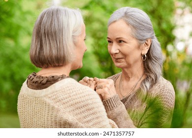 A lesbian couple holds hands and smiles at each other while camping in a lush green forest. - Powered by Shutterstock