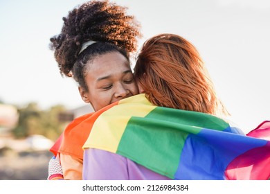 Lesbian Couple Hugging Together At Gay Pride Parade With LGBT Rainbow Flag - Equality And Love Concept