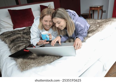 Lesbian couple lying on bed and using laptop together - Powered by Shutterstock