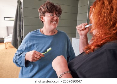 Lesbian couple in pajamas brushing teeth in bathroom - Powered by Shutterstock