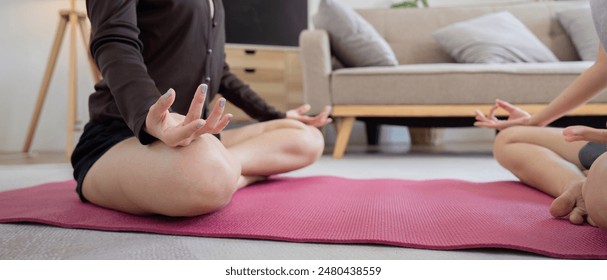 Lesbian Couple Practicing Yoga Together at Home, Engaging in Stretching Exercises on a Pink Mat in a Modern Living Room - Powered by Shutterstock