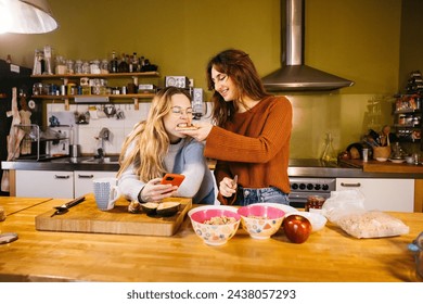 A lesbian couple preparing breakfast and sharing a toast, in the cozy atmosphere of their kitchen at home. - Powered by Shutterstock