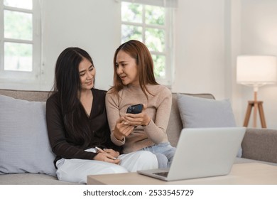 Lesbian Couple Relaxing in Modern Living Room with Laptop and Smartphone, Embracing Love and Technology - Powered by Shutterstock