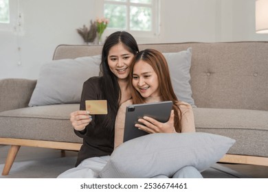 Lesbian Couple Shopping Online with Credit Cards, Happy Women Using Tablet for Online Shopping in Cozy Living Room - Powered by Shutterstock