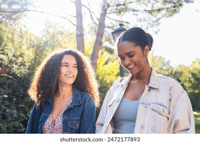 Lesbian couple of two African-American girls walking down the street on a sunny morning. They smile and have fun while taking a stroll in the city park. - Powered by Shutterstock