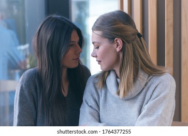 Lesbian couple of women on a date in a cafe. Two gay girlfriends hold hands and flirt. Tactile sensations. Lgbt.