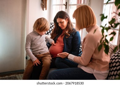 Lesbian family with child at home. Happy mothers with adopted child, pregnant couple with kid.