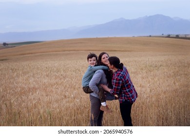 Lesbian Moms With A Young Boy. In A Wheat Field In The Country. The Boy Is Getting Piggyback From His Mother. 