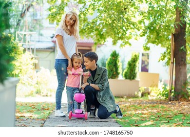 Lesbian parents walking with daughter in the park. Little girl want to ride her pink scooter. Happy LGBT family spending time together. - Powered by Shutterstock