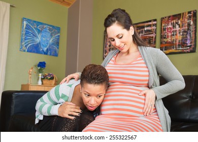 Lesbian spouse of pregnant woman listening to her womb