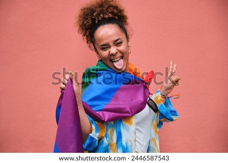 Lesbian woman is posing with a rainbow flag celebrating Pride Month.